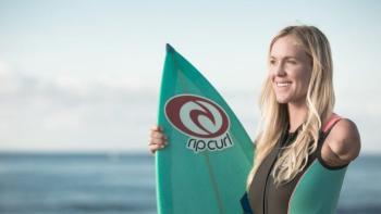 young woman with one arm holding a surfboard