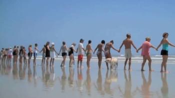 line of people standing on a beach holding hands